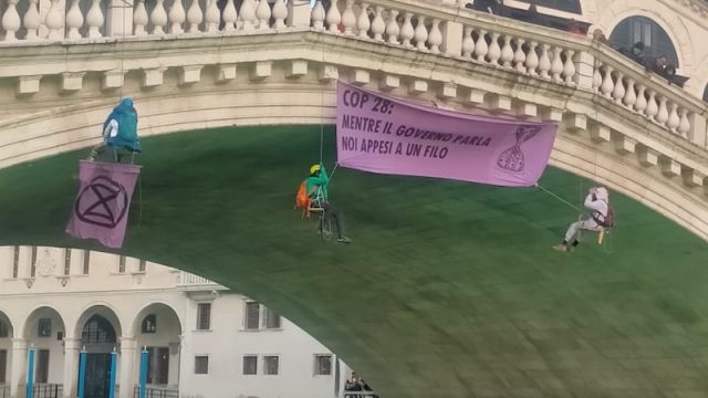 Venezia – Attivisti del clima colorano di verde il Canal Grande e si appendono al Ponte di Rialto